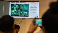 A journalist takes a photo of a presentation by the Philippine Coast Guard showing alleged Chinese activities in Scarborough Shoal, during a press conference in Manila on May 20, 2024. (Photo by JAM STA ROSA / AFP)