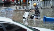 This photo taken on May 19, 2024 shows a man pushing his scooter along a flooded street following heavy rains in Nanning, in China's southern Guangxi region. (Photo by AFP)