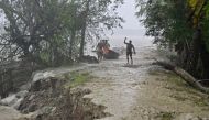 People walk on a damaged embankment along the Sonatola river during heavy rainfall in Patuakhali on May 27, 2024, following the landfall of Cyclone Remal in Bangladesh. Photo by Munir Uz Zaman / AFP