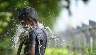 A boy plays with water during a hot summer day in Chennai on May 28, 2024. (Photo by R.Satish Babu / AFP)