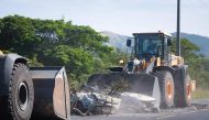 A tractor clears branches and a smashed car from a roadblock on the RT1 near the Ondemia district in Paita in France's Pacific territory of New Caledonia, June 4, 2024. (Photo by Delphine Mayeur / AFP)