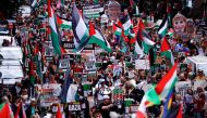 Protesters hold placards and wave Palestinian flags as they take part in a 