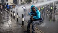 A protester reacts as a Kenyan police water canon sprays water at them during a demonstration against tax hikes as Members of the Parliament vote the Finance Bill 2024 in downtown Nairoibi, on June 20, 2024. (Photo by LUIS TATO / AFP)
 