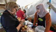 Ibtissem Mahtout (R) speaks with a customer who has come to pick up or buy their produce during the Friday market at an educational farm in Zeralda, west of Algiers on May 30, 2024. Photo by AFP.