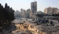 People walk on rubble at the damaged UNRWA building complex in western Gaza City's Al-Sinaa neighbouhood on July 12, 2024. (Photo by Omar Al Qattaa / AFP)
