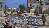 Palestinians walk past sewage water and a garbage dump on a street in Deir el-Balah in the central Gaza Strip on July 23, 2024. Photo by Eyad BABA / AFP