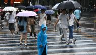 People walk through a rainstorm in Beijing on July 30, 2024. (Photo by Pedro PARDO / AFP)