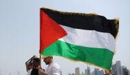 A man holding a Palestinian flag walks with others towards the Imam Muhammad bin Abdul Wahhab Mosque in Doha to bid farewell Hamas leader Ismail Haniyeh after his killing in Tehran. Photo by KARIM JAAFAR / AFP