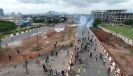 This aerial view shows protestors runing from clouds of tear gas fired by Nigerian security forces during the End Bad Governance protest in Abuja on August 2, 2024. Photo by Kola Sulaimon / AFP
