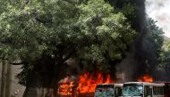 Buses are seen on fire at the Bangabandhu Sheikh Mujib Medical University premises after a clash between students and government supporters during a protest in Dhaka on August 4, 2024. (Photo by Abdul GONI / AFP)

