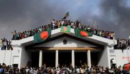 Anti-government protestors display Bangladesh's national flag as they storm Prime Minister Sheikh Hasina's palace in Dhaka on August 5, 2024. Photo by K M ASAD / AFP