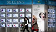 People walk past a real estate agents display in Melbourne on August 6, 2024. (Photo by William WEST / AFP)