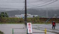 A man walks past a flooded road in the wake of 