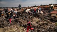 A Red Cross officer runs for help following a landfill collapse in Kampala on August 10, 2024. (Photo by BADRU KATUMBA / AFP)

