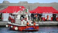 Divers of the Vigili del Fuoco, the Italian Corps. of Firefighters arrive in Porticello harbor near Palermo, with a third body at the back of the boat on August 21, 2024, two days after the British-flagged luxury yacht Bayesian sank. (Photo by Alberto PIZZOLI / AFP)
