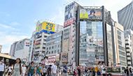 Pedestrians cross an intersection in the Shinjuku area of central Tokyo on August 13, 2024. (Photo by Richard A. Brooks / AFP)

