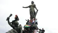 Protesters climbs on the statue 'Le Triomphe de la Republique' at Place de la Nation to demonstrate against the French President's 