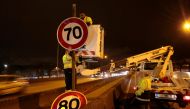 City workers set a 70 kph speed limit sign after removing a 80 kph one, on Paris' ringroad, the boulevard peripherique, on January 7, 2014. Photo by JACQUES DEMARTHON / AFP