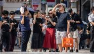 People wait to cross a street during hot weather in Tokyo on September 19, 2024. (Photo by Yuichi Yamazaki / AFP)