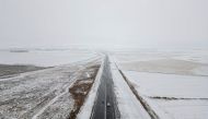 This aerial view taken on September 21, 2024, shows cars driving on a road next to snowfall on farmlands near Warden, Free State province, South Africa. (Photo by Wikus de Wet / AFP)