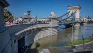 Pedestrians walk across The Szechenyi Chain Bridge as workers help to protect a tunnel with sandbags, near Buda Castle on September 21, 2024. (Photo by FERENC ISZA / AFP)