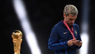 France's forward #07 Antoine Griezmann looks at his silver medal as he walks past the FIFA World Cup trophy during the trophy ceremony after France lost the Qatar 2022 World Cup final football match between Argentina and France at Lusail Stadium in Lusail, north of Doha on December 18, 2022. Photo by Kirill KUDRYAVTSEV / AFP