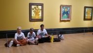 A handout picture from the Just Stop Oil climate campaign group shows three activists sitting on the floor under Vincent van Gogh's 