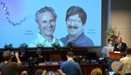 Olle Kaempe, member of the Nobel Assembly, speaks to the media in front of screen displaying a picture of this year's laureates Victor Ambros and Gary Ruvkum. (Photo by Jonathan Nackstrand / AFP)