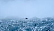 (Files) This photograph taken on May 2, 2021, shows a helicopter flying over the Khumbu glacier in the Mount Everest region. (Photo by Prakash Mathema / AFP) 
