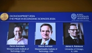 A screen shows the laureates (L-R) Turkish-American Daron Acemoglu and British-Americans Simon Johnson and James Robinson of the 2024 Sveriges Riksbank Prize in Economic Sciences in Memory of Alfred Nobel during the announcement by the Royal Swedish Academy of Sciences in Stockholm, Sweden on October 14, 2024. (Photo by Christine Olsson / TT NEWS AGENCY / AFP) 