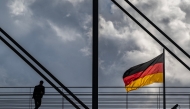A man pauses on a pedestrian bridge as a German flag flies over the Reichstag building in Berlin on October 23, 2024. (Photo by John MACDOUGALL / AFP)
