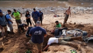 A group of people try to dig up a car in search of victims buried on the riverbank, on November 1, 2024, after a flooding devastated the town of Paiporta, in the region of Valencia, eastern Spain. (Photo by Manaure Quintero / AFP)