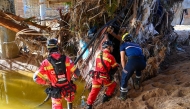 Portuguese firefighters and a civil protection worker search for victims in debris beside a riverbank on November 2, 2024, in the aftermath of devastating floolding in the town of Paiporta, in the region of Valencia, eastern Spain. Photo by JOSE JORDAN / AFP