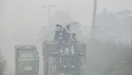 Commuters ride along a highway engulfed in smog, on the outskirts of Lahore on November 6, 2024. (Photo by Arif Ali / AFP)
