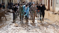 People with masks and soldier remove mud in a flooded street on November 6, 2024, in Catarroja, in the region of Valencia, eastern Spain, in the aftermath of deadly floods. (Photo by CESAR MANSO / AFP)

