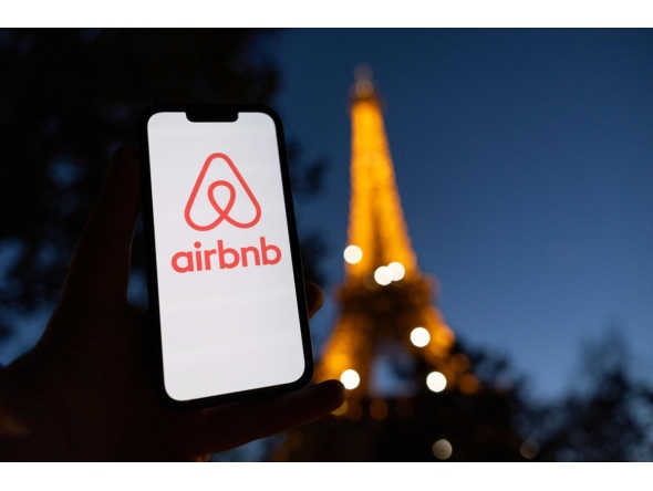 This photograph taken on October 28, 2024 shows the logo of short-term housing rentals online application Airbnb on a smart-phone screen in front of the Eiffel Tower in Paris. Photo by Grégoire CAMPIONE / AFP
