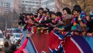 People (lower L) welcome members of the North Korean women's under-17 football team (R) on a street in Pyongyang on November 9, 2024. North Korea beat Spain on penalties November 3 in the Dominican Republic to clinch a record third Women's World Cup at under-17 level, adding it to their title in the under-20 version in September. (Photo by KIM Won Jin / AFP)
