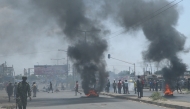 A Mozambican soldier walks away as protesters burn tyres during a demonstration against the government in Maputo on December 6, 2024.  (Photo by Amilton Neves / AFP)

