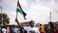 A supporter of Former Ghana President and presidential candidate of the National Democratic Congress (NDC) party John Mahama holds a flag of the party's colours as he celebrates in Accra on December 8, 2024. (Photo by OLYMPIA DE MAISMONT / AFP)
