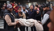 Palestinians carry a body as they prepare for a funeral at the al-Awda Hospital at the Nuseirat refugee Camp in the central Gaza Strip on December 7, 2024. (Photo by Eyad BABA / AFP)
