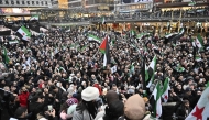 Members of the Syrian community hold Syrian flags as they rally on December 8, 2024 on Sergel's Square in Stockholm, Sweden, to celebrate the end of Syrian dictator Bashar al-Assad's rule after rebel fighters took control of the Syrian capital Damascus overnight. (Photo by Jonas EKSTROMER / TT NEWS AGENCY / AFP) / Sweden OUT
