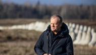Poland's Prime Minister Donald Tusk speaks with concrete anti-tank barriers in the background during his inspection of the first completed section of fortifications 