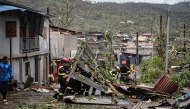 This handout aerial photograph taken and released by the French Securite Civile on December 15, 2024 shows French Security Civile members removing debris in Combani, on the French Indian Ocean territory of Mayotte, after the cyclone Chido hit the archipelago. (Photo by Handout / Securite Civile / AFP)
