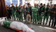 Palestinian Red Crescent paramedics pray by the body of their fallen colleague Mahmud al-Muhadad, who was reportedly killed in an Israeli air strike in Jabalia in the northern Gaza Strip, as it lies at the Ahli Arab hospital, also known as the Baptist hospital, in Gaza City on January 4, 2025. (Photo by Omar AL-QATTAA / AFP)
