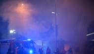 Members of the fire brigade extinguish a fire at merchandise stall outside the Etihad Stadium in Manchester, north west England, on January 29, 2025, ahead of the UEFA Champions League football match between Manchester City and Club Brugge. (Photo by Paul ELLIS / AFP)
