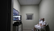 Two inmates watch a virtual trial at the Counter-Terrorism Confinement Centre (CECOT) mega-prison, where hundreds of members of the MS-13 and 18 Street gangs are being held, in Tecoluca, El Salvador on January 27, 2025. (Photo by Marvin RECINOS / AFP)
