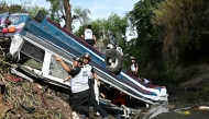 Volunteer firefighters work at the scene of an accident in which a bus fell down a ravine in Guatemala City on February 10, 2025. (Photo by Johan ORDONEZ / AFP)

