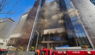 Firefighters work at the scene of a fire at a construction site of the Banyan Tree Hotel in the southern port city of Busan on February 14, 2025. (Photo by YONHAP / AFP) 