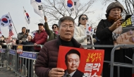 Supporters of arrested and impeached South Korean President Yoon Suk Yeol hold a placard showing a picture of Yoon and reading 