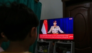 Yemenis in Sanaa watch a televised statement by the Huthi military spokesman Yahya Saree announcing the group launched an attack on a US aircraft carrier in the Red Sea on March 16, 2025. Photo by Mohammed HUWAIS / AFP.